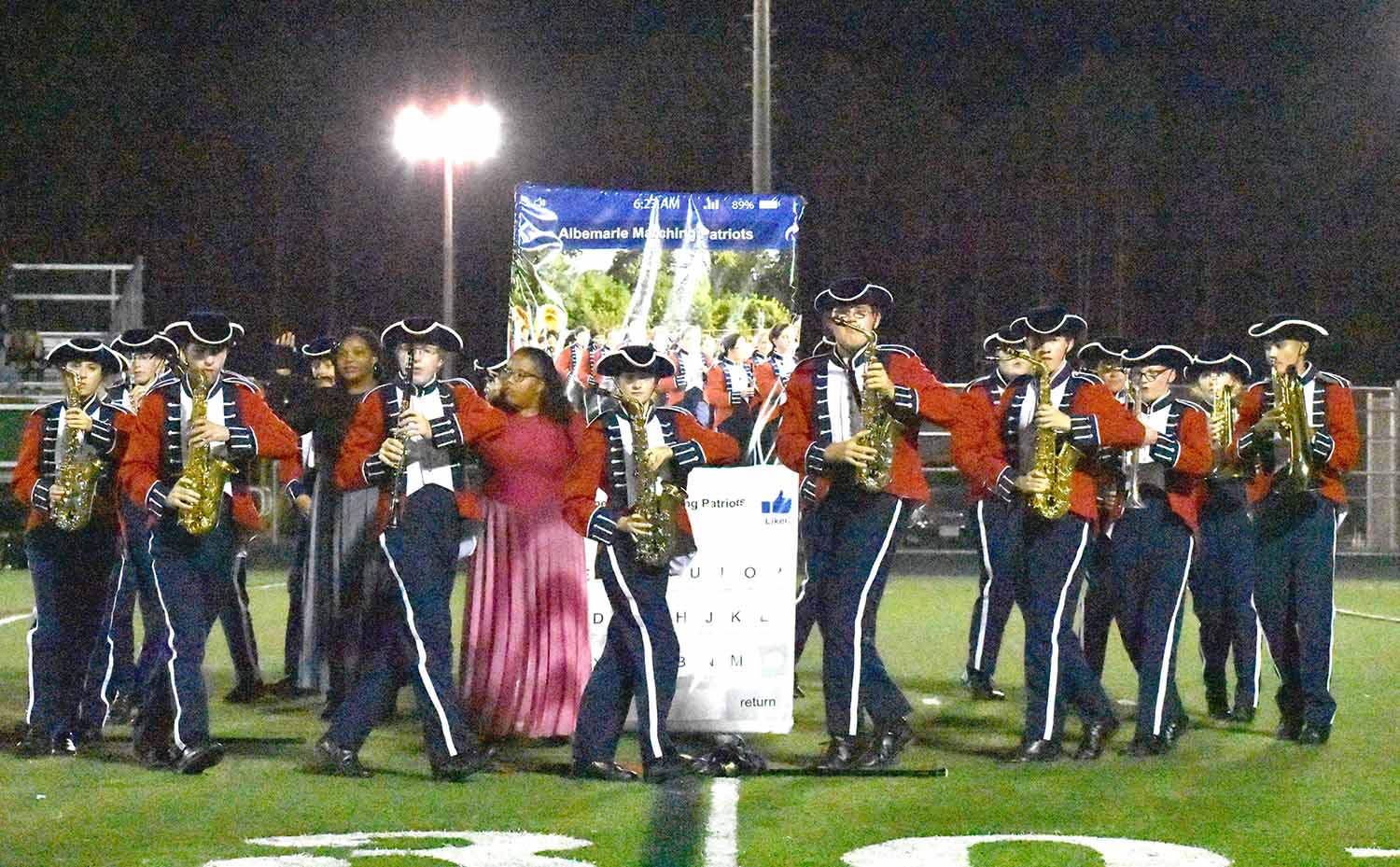 Junior Max Rosen, senior Aryawn Shackelford, and juniors Stephanie Scheiber and Jesse Elena perform in front of a phone prop during the Oct. 5 home football game at halftime.