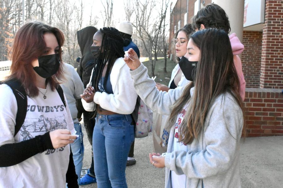 Freshman Evelyn Springston accepts a white ribbon from senior organizer Yatzil Romero-Rodriguez while walking in from the bus drop-off. 