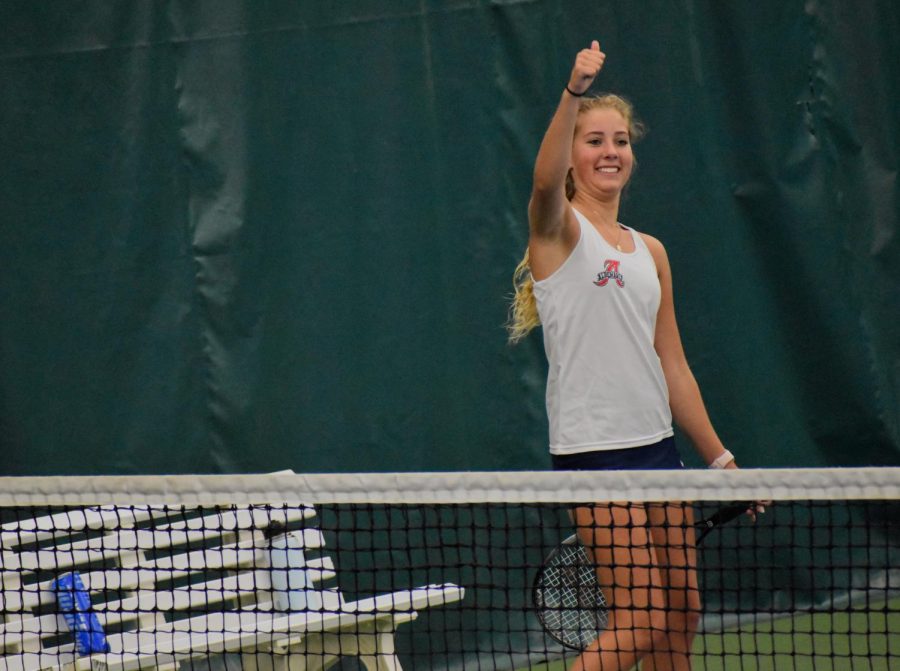 Freshman Macy Mooy gives friends in the stands a thumbs up after winning her match 2-0.