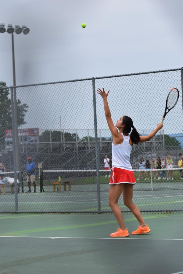 Senior Mia Shen tosses the tennis ball in the air as she serves the match winning point. 
