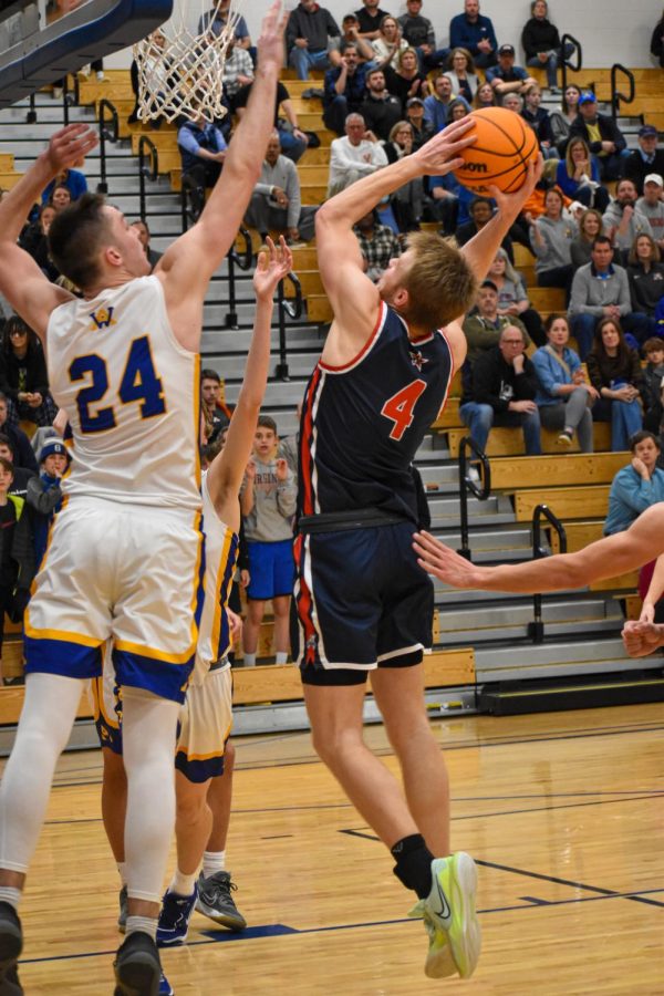 Senior Carter Wesson jumps over Western player senior Josh Sime to make a layup in the second half of the game. 