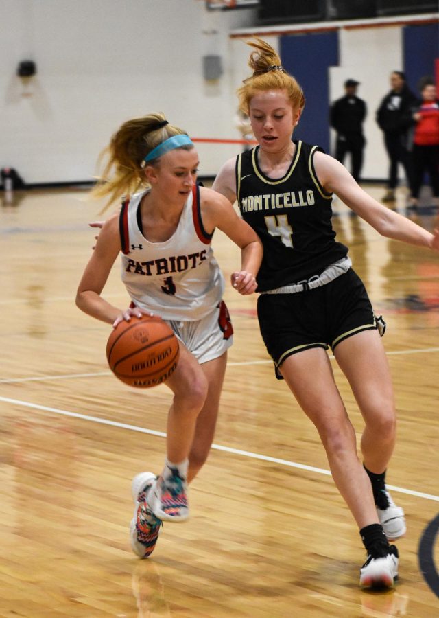 Senior Kaley Maynard carries the ball down the court, shoving off Monticello defender in an attempt to reach the basket. 