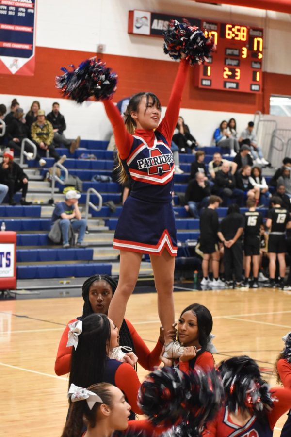 Senior Joy Scofield performs a cheerleading stunt while supported by teammates between the third and fourth quarters of the game. 