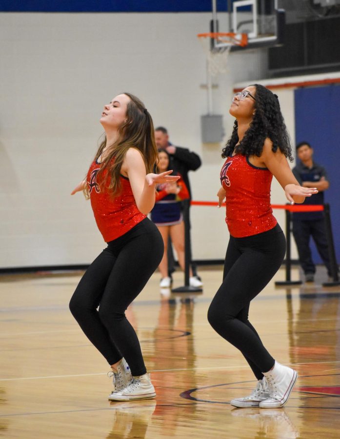 Sophomore Lea Johns (left) and 9th grader Hannah Carpenter (right) dip back as they perform the Dance Team half-time show during the Monticello home game on 1/27.
