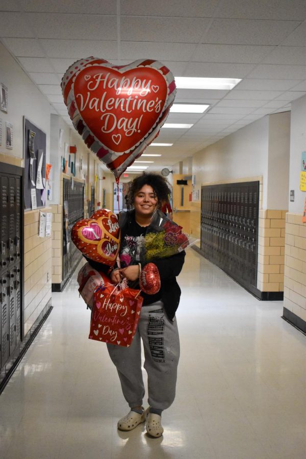 Sophomore Ahniyah Snead holds up red heart balloons, gift bags and carnations to deliver for V-Day celebrations. The proceeds from V-Day Thang sales went to support the Giordano family. 