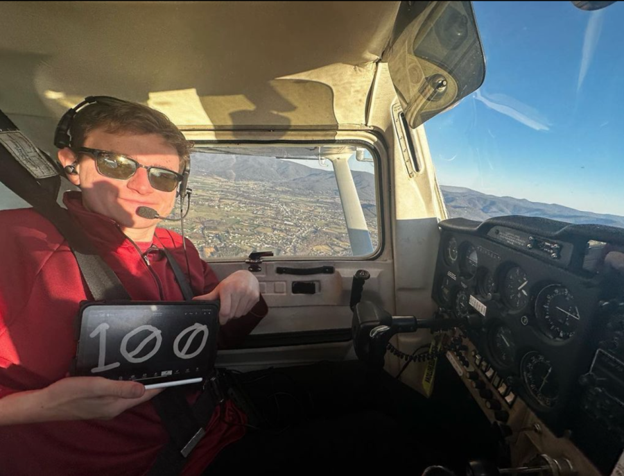Senior Graham DeVito holds up a 100 sign mid-air to commemorate his 100th hour of flying.