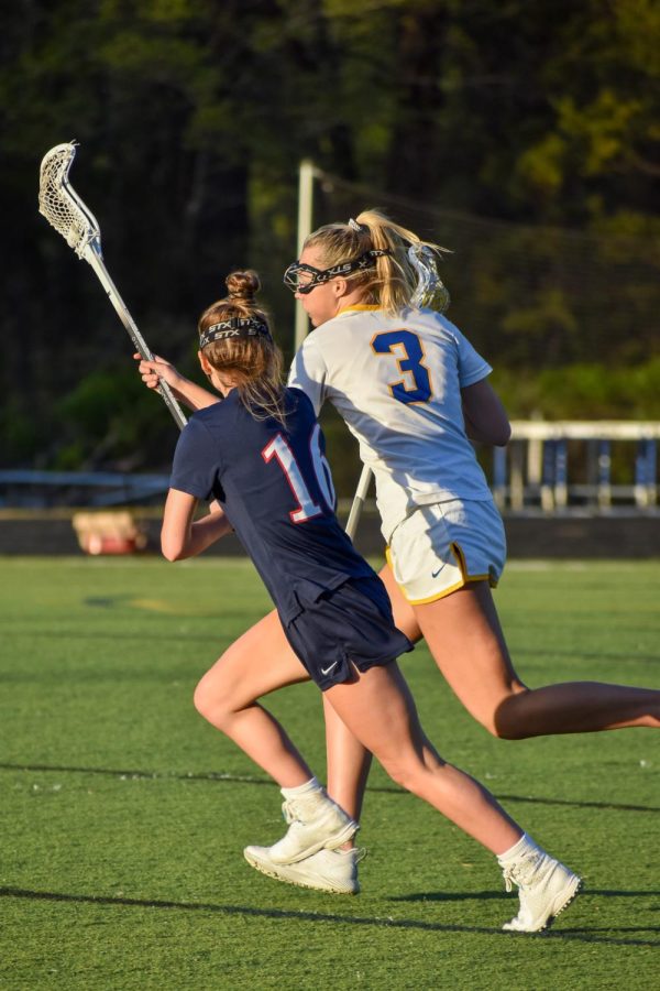 Senior Gracie Fugleberg defends Western player as they run down the field, blocking her passing space with her stick.
