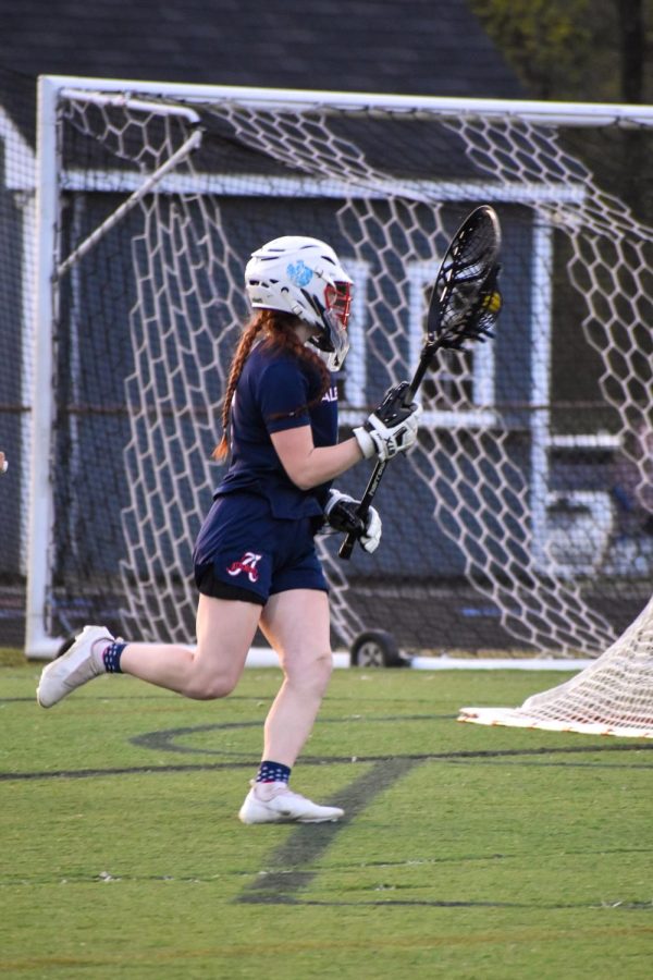 Sophomore Emma Bingler runs outside of the crease, looking for a pass up the field after saving a shot by WAHS. 