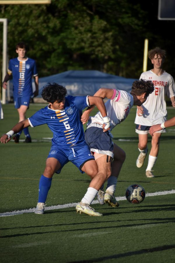 Senior captain Luke McClung shoves through WAHS defender to continue pushing the ball upfield in the first half of the game.